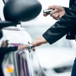 Ladrón intentando robar un coche mientras un sistema LoJack localiza el vehículo.