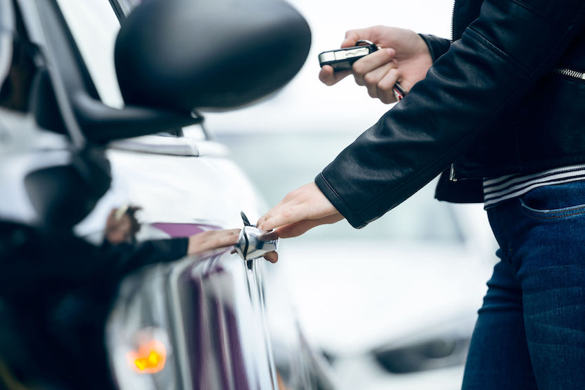 Ladrón intentando robar un coche mientras un sistema LoJack localiza el vehículo.