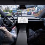 Interior de un Tesla con el sistema FSD supervisado circulando en entorno urbano con peatones