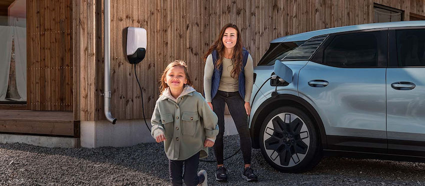 Familia junto a un coche eléctrico cargando en una vivienda