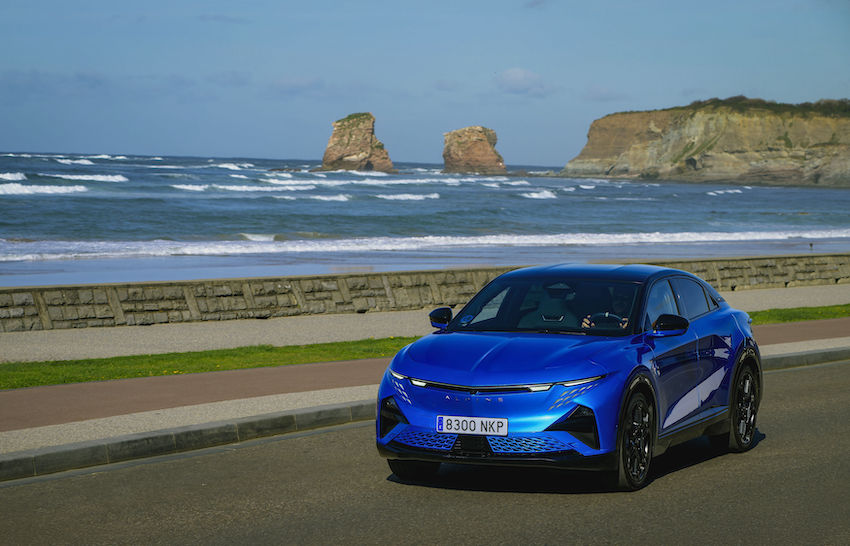 Alpine A390 GT azul circulando junto al puerto durante un viaje de verano.