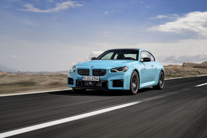 BMW M2 Coupé con M xDrive en color azul circulando por una carretera abierta.